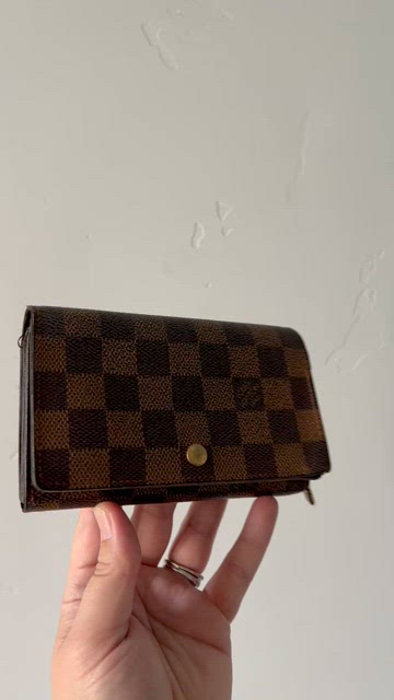 A Louis Vuitton wallet standing on a wood surface with the Chase